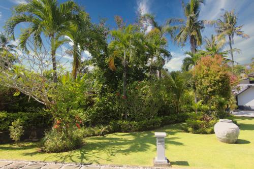 a garden with palm trees and a vase in the grass at Villa Bayu Lovina 2bedroom villa, private pool in Lovina