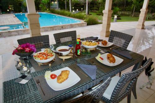 a table with plates of food on it next to a pool at Villa Bayu Lovina 2bedroom villa, private pool in Lovina