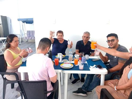 a group of people sitting around a table drinking orange juice at Hurin Hotel in Ica