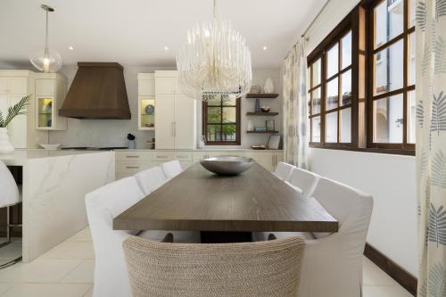 a kitchen with a wooden table and white chairs at Paseo Miraflores 7 At Las Catalinas in Tempate