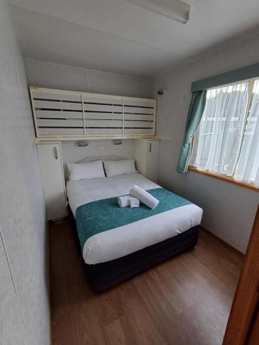 a bedroom with a bed with two towels on it at Casuarina Cabins in Nelson