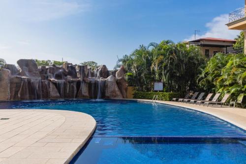 a swimming pool with a waterfall in a resort at Sunrise 6- Ocean View 2 Br Condo, Steps To The Beach in Tamarindo