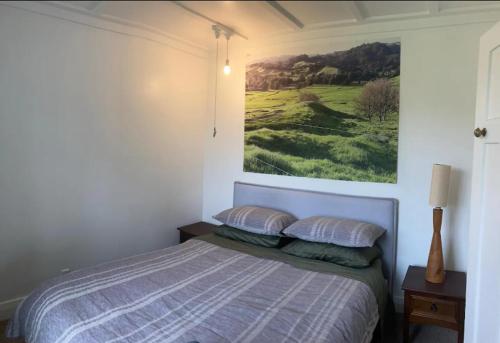 une chambre avec un lit avec un tableau sur le mur dans l'établissement Cottage at Te Kaone, à Broadwood