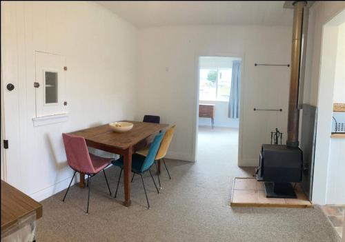 une salle à manger avec une table, des chaises et une télévision dans l'établissement Cottage at Te Kaone, à Broadwood