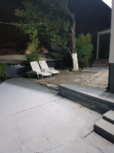 two white chairs sitting outside of a house at Apartman Deni in Tuzla