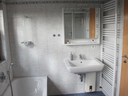 a white bathroom with a sink and a tub at Wehner Comfortable holiday residence in Marl