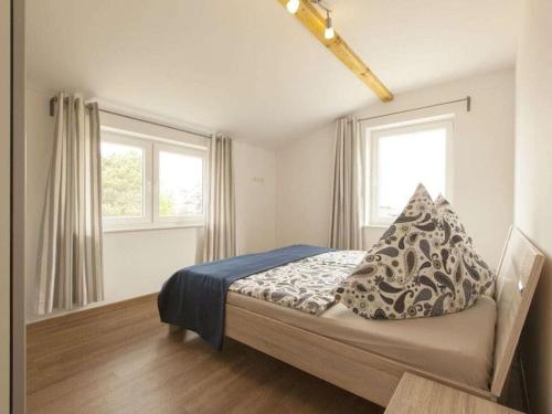 a bedroom with a bed with two windows and a blue blanket at 1 - Eilrich Comfortable holiday residence in Thiessow