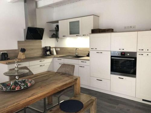 a kitchen with white cabinets and a wooden table at Fehnhuus Comfortable holiday residence in Timmel
