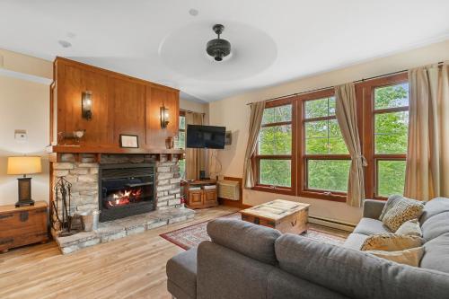 a living room with a couch and a fireplace at Les Eaux - 2bdrs W Pool & Hot Tub Near Village in Mont-Tremblant