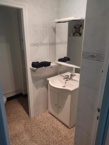 une salle de bain blanche avec un lavabo et un miroir dans l'établissement Hespérides, à Fort-Mahon-Plage