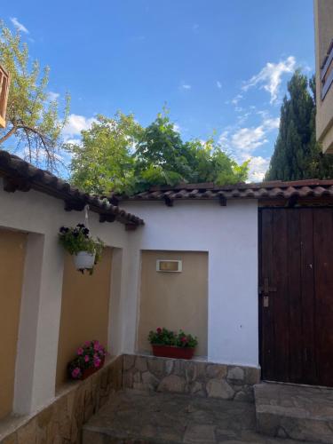 a white house with a wooden door and flowers at Deers in Bansko
