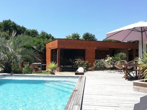 une piscine avec une terrasse et une maison dans l'établissement Villa piscine chauffée,5ch ,climatisation, bar extérieur, à Lacanau
