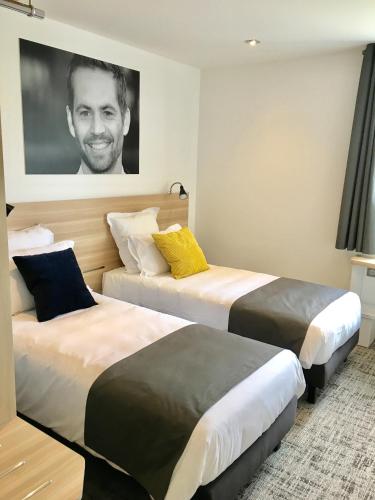 a hotel room with two beds and a picture of a man at Brit Hotel Martigues Nord in Martigues