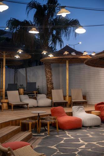 a patio with couches and chairs and a palm tree at Neve Eilat Hotel By Atlas Hotels in Eilat