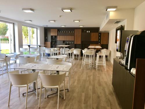 a dining room with tables and white chairs at Brit Hotel Martigues Nord in Martigues