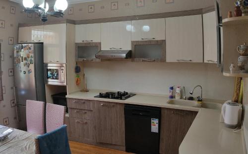 a kitchen with white cabinets and a black refrigerator at Cozy House in Bina, Bolluq in Baku