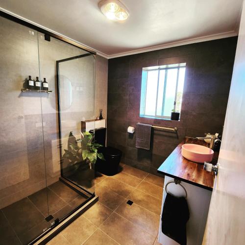 a bathroom with a glass shower and a sink at Casa Luna Beachside Apartment in Henley Beach South