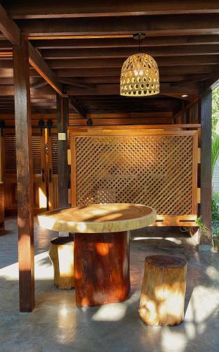 a wooden table and two logs under a pavilion at Golden Chenang Village in Pantai Cenang