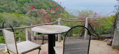 a table and chairs on a balcony with pink flowers at Casa Macondo in Puerto Ángel