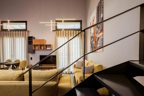 a living room with a staircase with chairs and a television at Urban Apartments in Chios