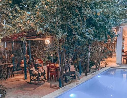 a swimming pool with trees and a table and chairs at Casa Daniels Guesthouse in Valladolid