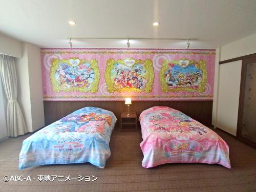 two beds in a room with a wall covered in paintings at Yuzawa Toei Hotel in Yuzawa