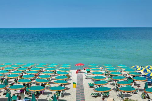 a bunch of chairs and umbrellas on a beach at Hotel Beaurivage in Fano