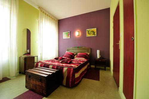 een slaapkamer met een bed met rode kussens bij Hôtel Bertrand in Bar-le-Duc