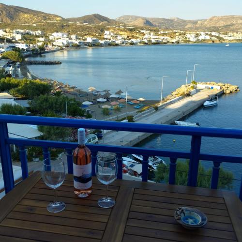a bottle of wine and two glasses on a table on a balcony at Light Blue in Makry Gialos