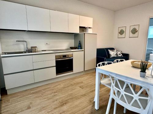 a kitchen with white cabinets and a dining table at Appartamento Sole in Numana