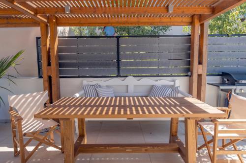 a wooden picnic table and chairs on a patio at Gioma Luxury Suites - Lake View - Jacuzzi in Agios Nikolaos