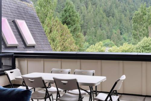 a white table and chairs on a balcony with trees at Lakeview Splendor- 7BR Penthouse Bliss Combo unit in Harrison Hot Springs