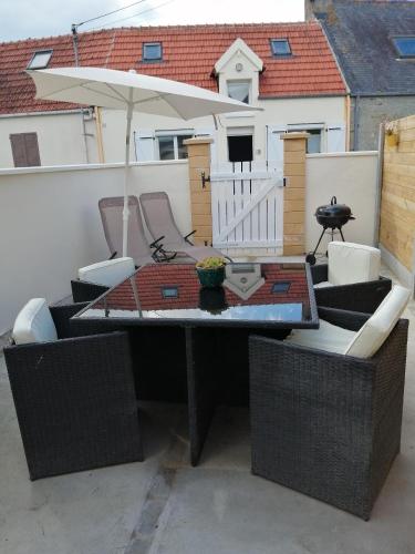 a table and chairs with an umbrella on a patio at le petit hameau in Fontenay-sur-Mer