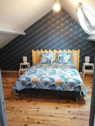 a bedroom with a bed with a blue comforter at le petit hameau in Fontenay-sur-Mer