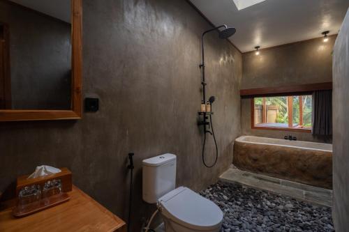 a bathroom with a toilet and a bath tub at Moonterra Villa Sebatu in Tampaksiring