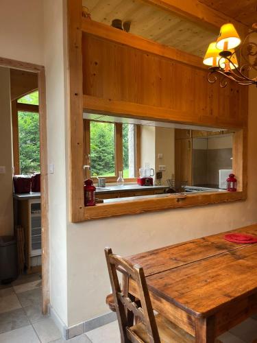 une salle à manger avec une table en bois et une cuisine dans l'établissement Appartement cosy avec jardin, à Saint-Jean-dʼAulps