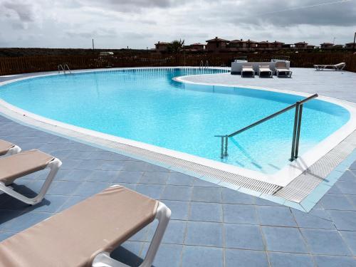 a large swimming pool with two chairs at Casa Solayla Origomare in Lajares