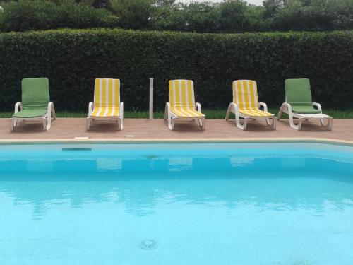 a group of four lawn chairs sitting next to a swimming pool at Happy Holiday Villa - Pool & Garden in Syracuse