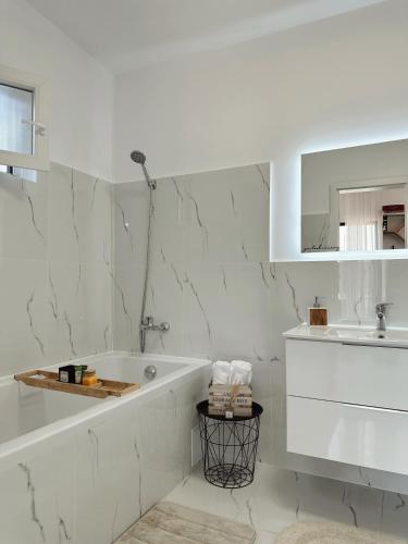 a white bathroom with a tub and a sink at Story Cabin Lake in Cîmpeneşti