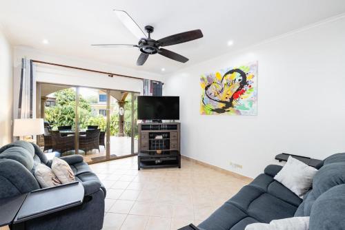 a living room with two couches and a flat screen tv at Sunrise 6- Ocean View 2 Br Condo, Steps To The Beach in Tamarindo