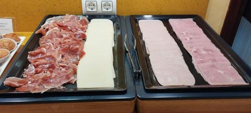 two trays of different types of meat on a counter at Hotel Torres Touriño in Sanxenxo