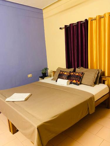 a bedroom with a large bed with yellow curtains at Paradise Inn Beach Resort in Varkala