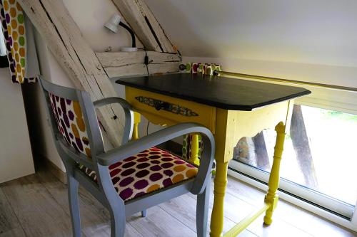 a yellow table and a chair next to a window at Le Lido in Sézanne