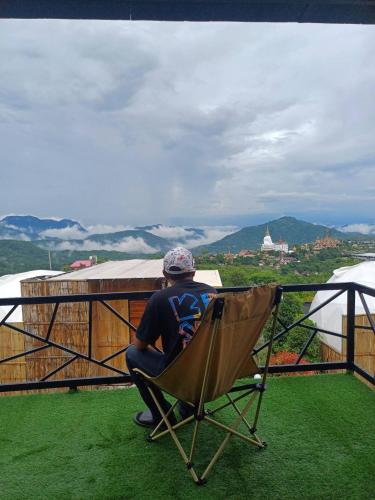 a man sitting in a chair on top of a balcony at Chill & View ชิววิว เขาค้อ in Ban Huai Phai