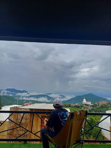 a man sitting in a chair looking out over a city at Chill & View ชิววิว เขาค้อ in Ban Huai Phai