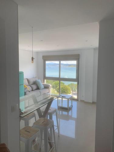 a white living room with a couch and a table at Luz de Mar in O Grove