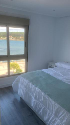 a bedroom with a large bed and a large window at Luz de Mar in O Grove