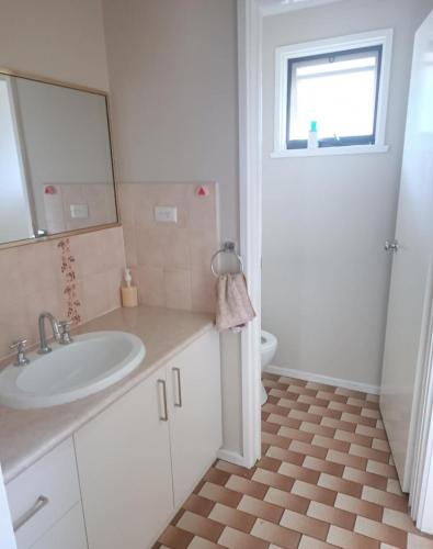 a white bathroom with a sink and a mirror at Spacious and cozy home next to Glen Waverley in Wantirna South