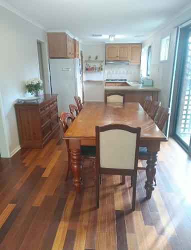 a kitchen with a wooden dining table and chairs at Spacious and cozy home next to Glen Waverley in Wantirna South