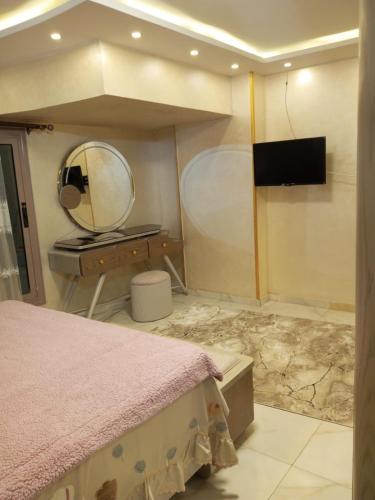 a bedroom with a bed and a mirror and a television at المنصوره in Ṭalkha
